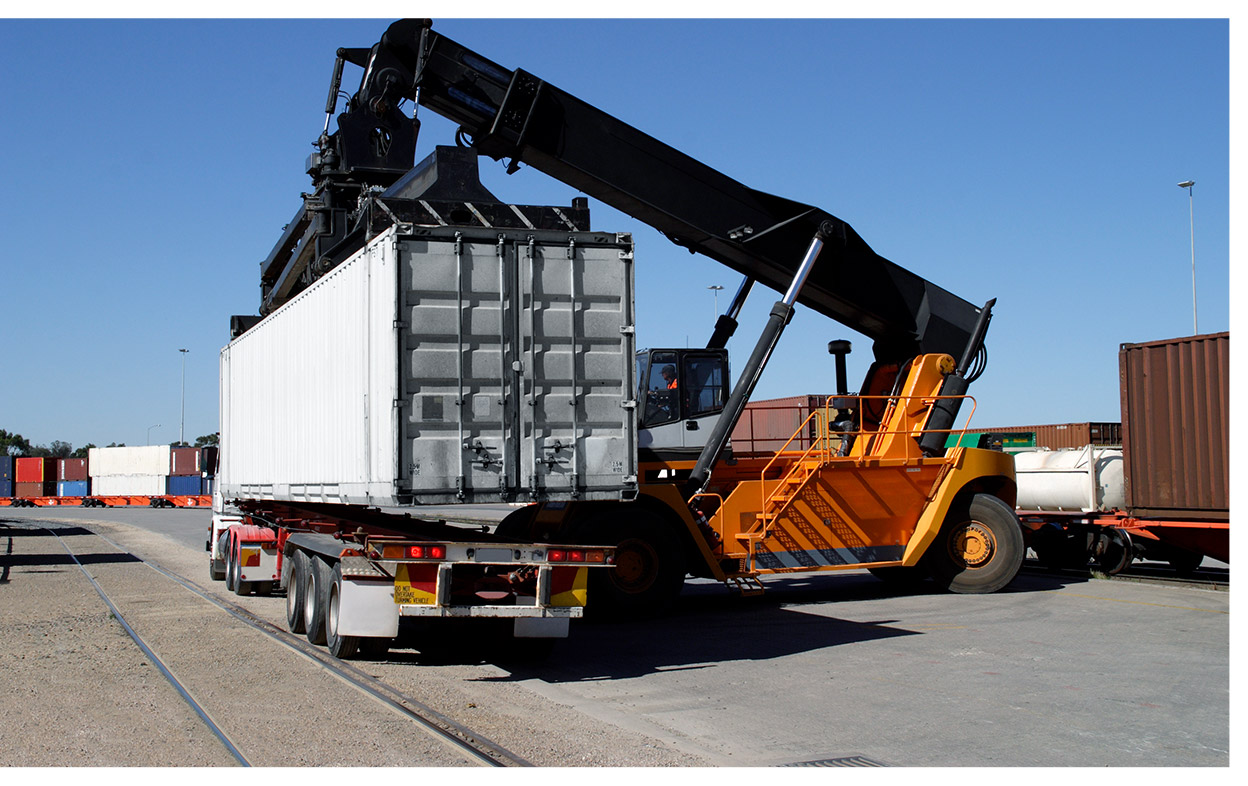 Hyster drayage crane lifting container carrying automotive products off flatbed